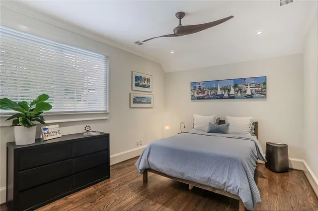 a bedroom with a bed a dresser and potted plant