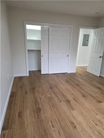 a view of an empty room with wooden floor and closet
