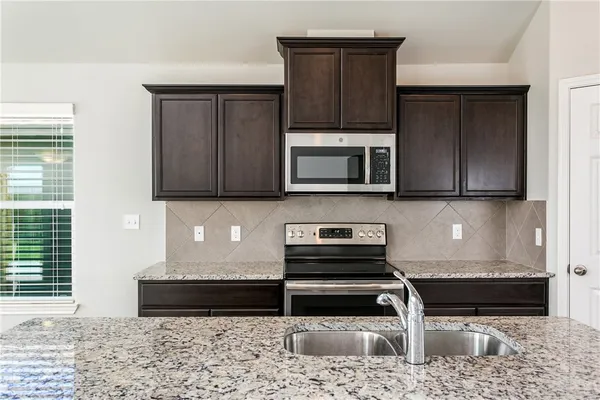 a kitchen with stainless steel appliances granite countertop a stove a microwave and a sink