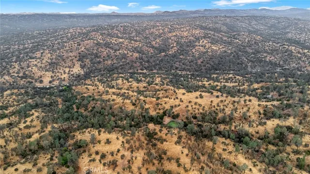 an aerial view of house with yard and mountain view in back