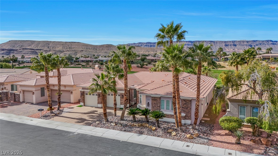 5015 Rivedro Street Las Vegas, NV 89135 - Photo 67 of 91 A terracotta-roofed residence with a stone facade, palm trees, and desert landscaping, offering scenic mountain views.