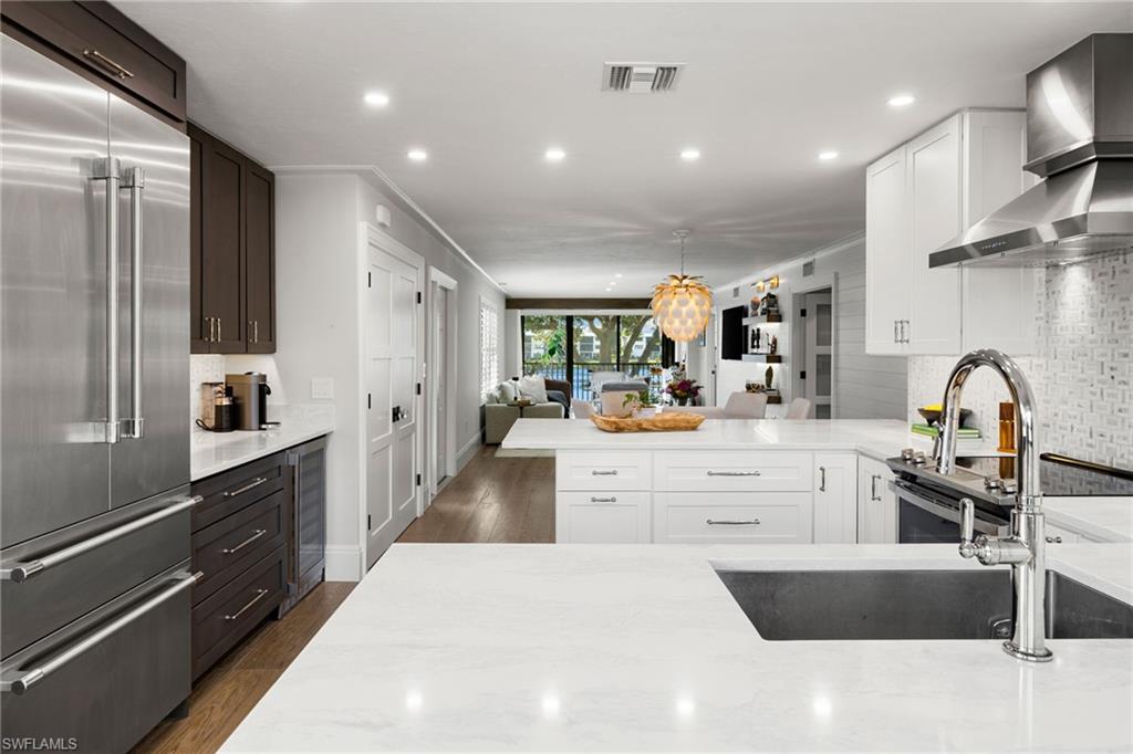 a large kitchen with stainless steel appliances kitchen island a sink dishwasher a stove and a refrigerator with wooden floor