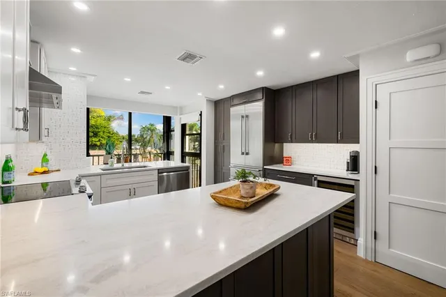 a kitchen with stainless steel appliances kitchen island granite countertop a sink dishwasher and refrigerator with wooden floor