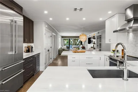 a large kitchen with stainless steel appliances kitchen island a sink dishwasher a stove and a refrigerator with wooden floor