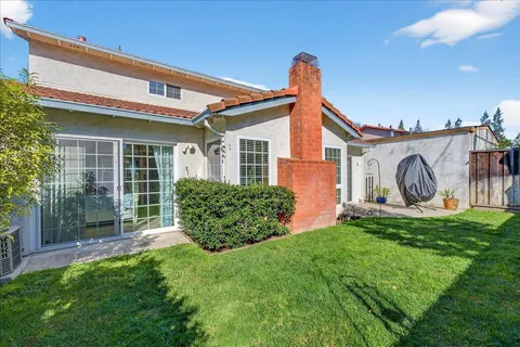 a view of a house with brick walls and a yard with plants