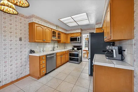 a kitchen with stainless steel appliances granite countertop a sink stove refrigerator granite counter tops wooden cabinets and a window