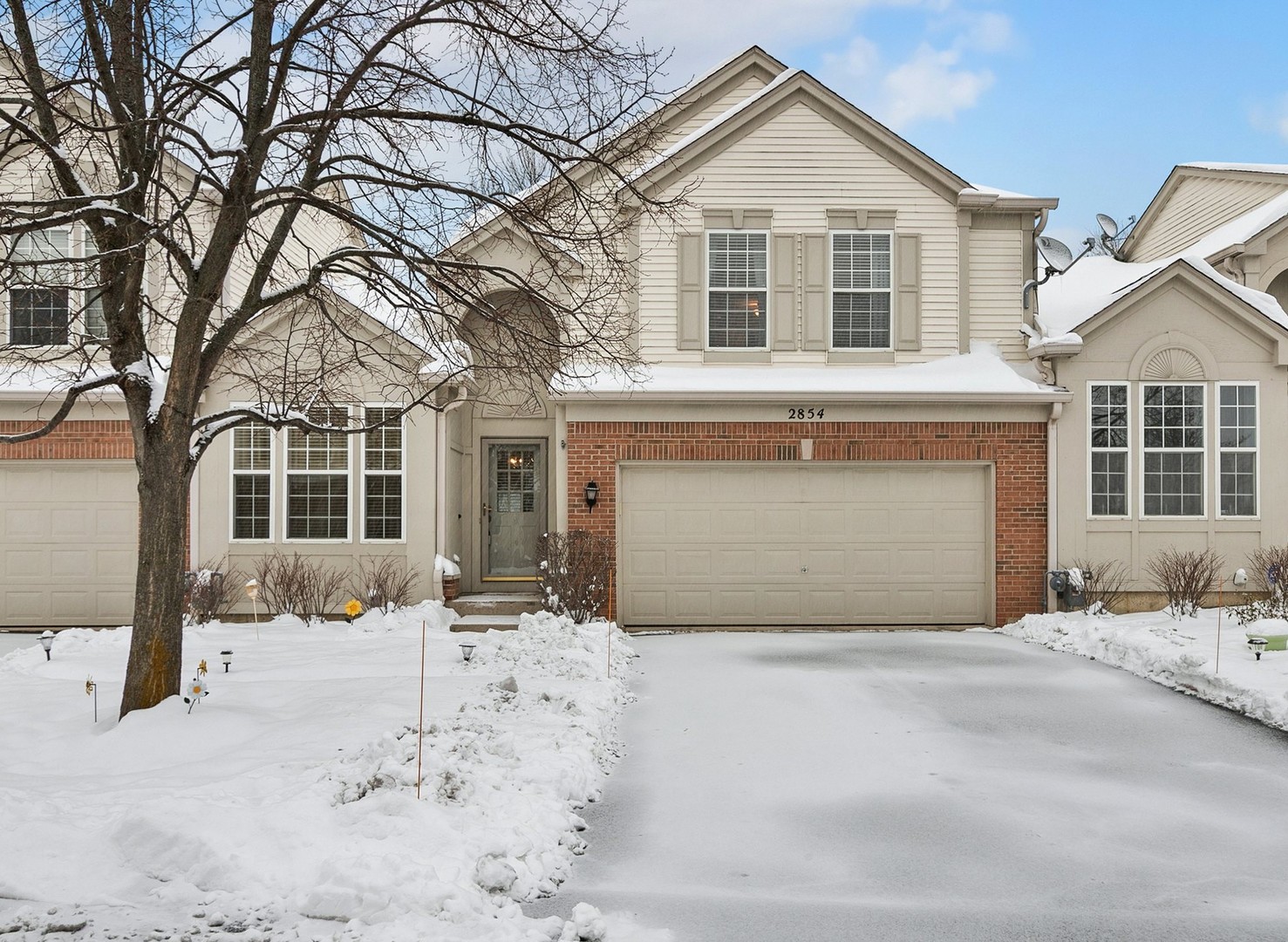 a front view of a house with a yard covered in snow