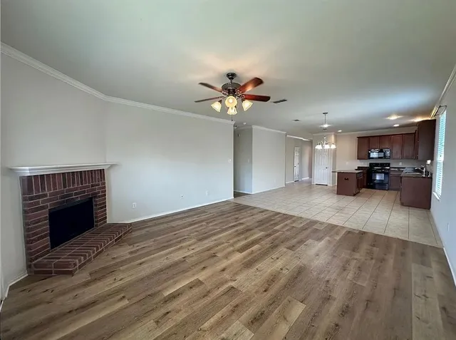 a view of an empty room with a kitchen and a fireplace