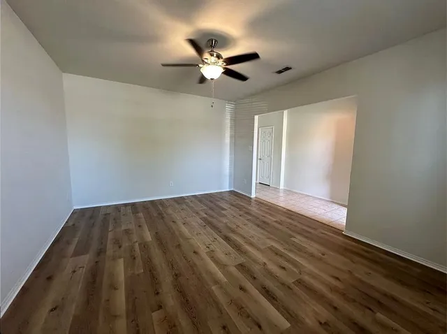 a view of an empty room with a window and wooden floor