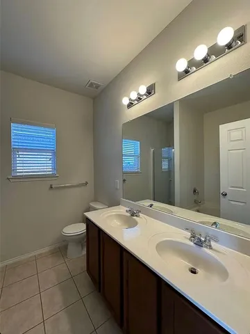 a bathroom with a double vanity sink a toilet and a mirror