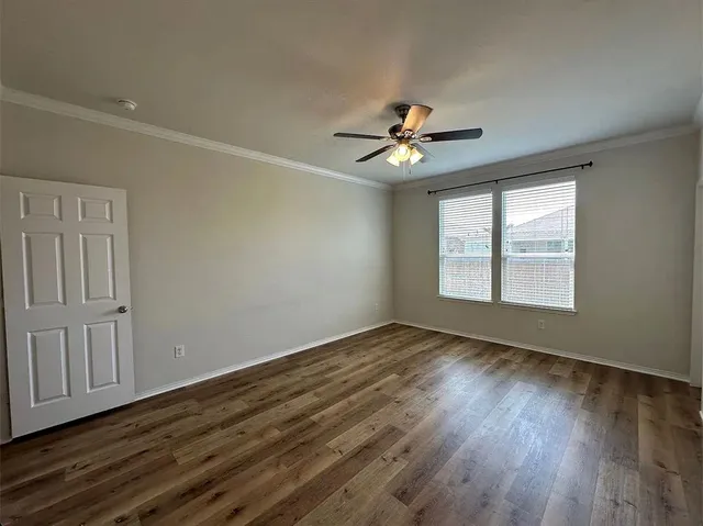 a view of an empty room with a window and wooden floor