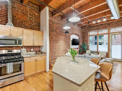 a kitchen with stainless steel appliances granite countertop a stove top oven a sink dishwasher and dining table with wooden floor