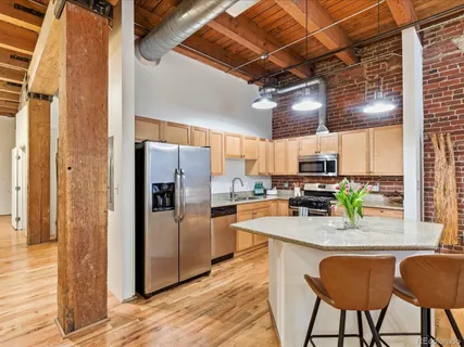 a kitchen with stainless steel appliances granite countertop a kitchen island a stove a refrigerator with a dining table and chairs