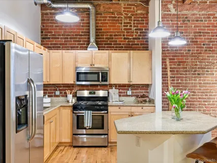 a kitchen with stainless steel appliances kitchen island granite countertop a stove a sink and a refrigerator
