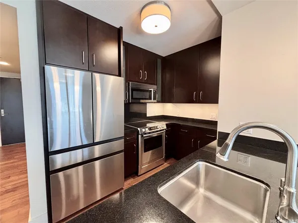 a kitchen with stainless steel appliances granite countertop a refrigerator a stove and a sink with wooden floor