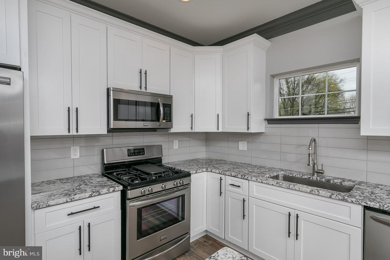 3601 Chapman Road Randallstown, MD 21133 - Photo 12 of 30 a kitchen with granite countertop white cabinets stainless steel appliances and a sink