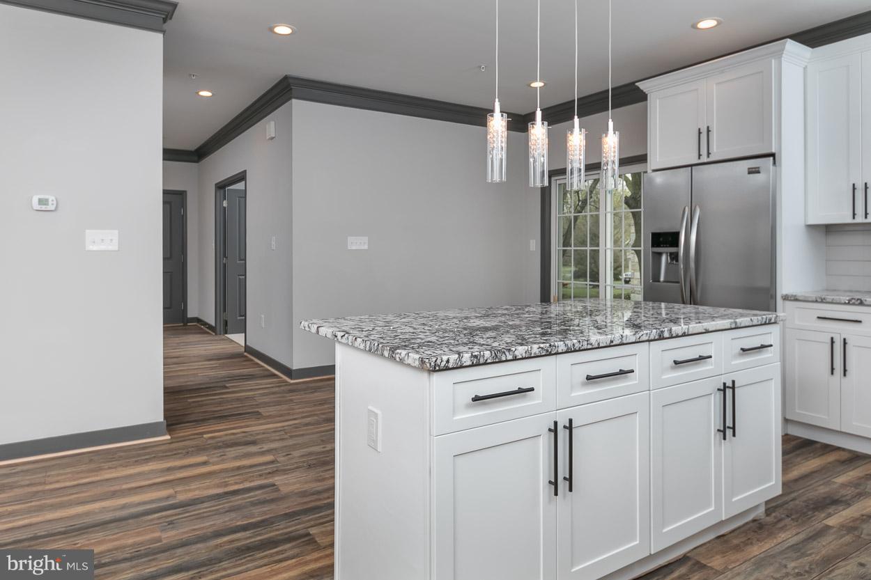 3601 Chapman Road Randallstown, MD 21133 - Photo 10 of 30 an open kitchen with granite countertop kitchen island white cabinetry and stainless steel appliances