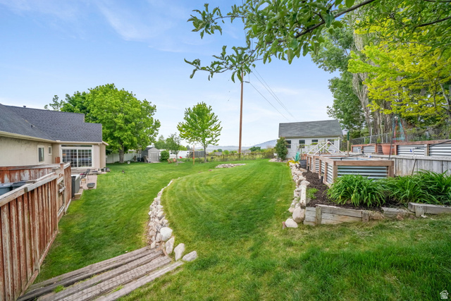 357 South 320 W Street Lindon, UT 84042 - Photo 34 of 41 Expansive backyard featuring a manicured lawn, a detached storage shed, multiple raised garden beds, a wood privacy fence, and mature trees