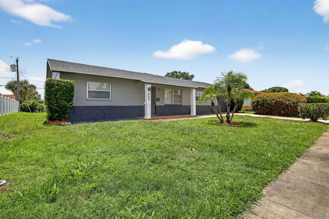 a view of an empty room with wooden floor kitchen appliances and a window