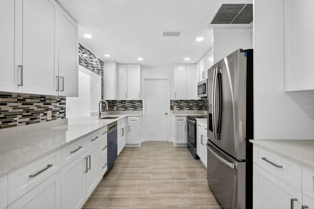 a kitchen with white cabinets and stainless steel appliances
