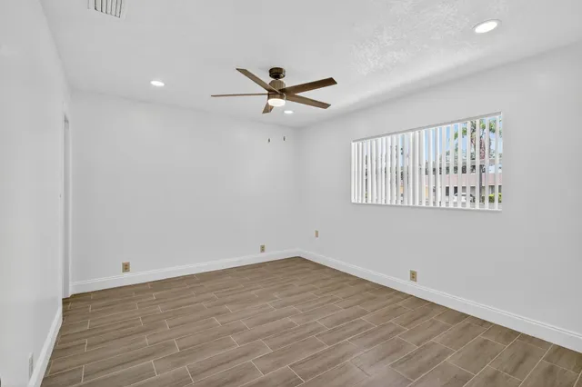 an empty room with wooden floor and a ceiling fan
