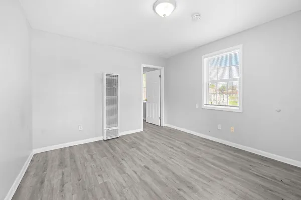 an empty room with wooden floor and windows