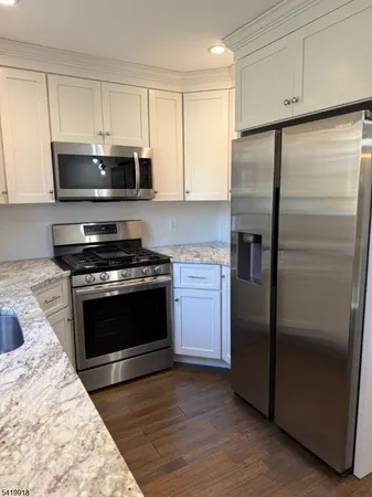 a kitchen with stainless steel appliances kitchen island granite countertop a stove a refrigerator and a microwave