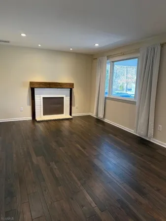an empty room with wooden floor fireplace and windows