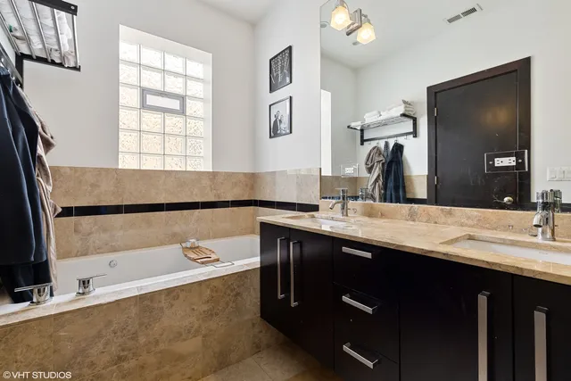 a bathroom with a tub a double vanity sink and a large mirror