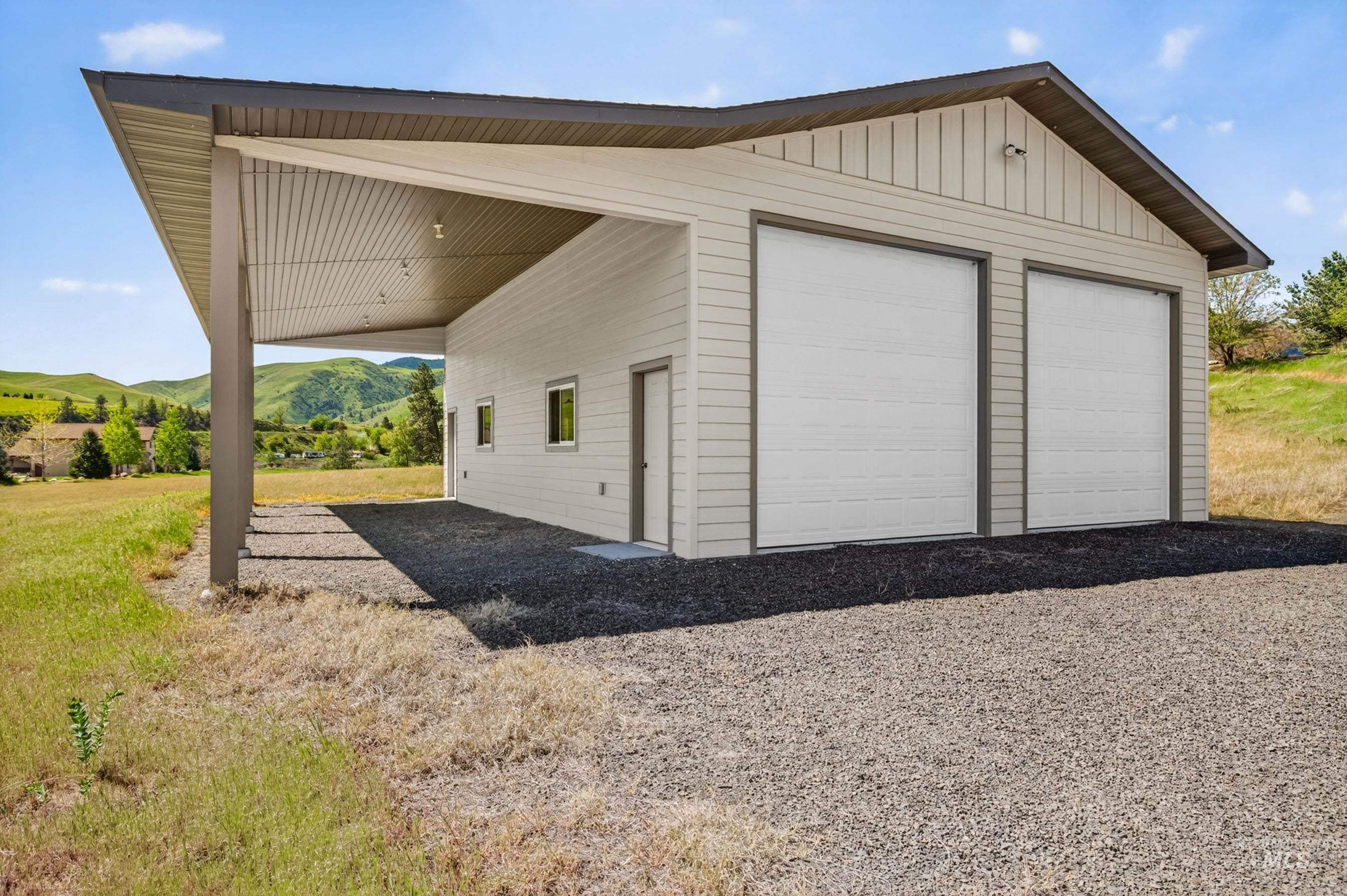 113 Deford Road White Bird, ID 83554 - Photo 44 of 49 Detached garage structure featuring two overhead doors, an extended carport, and a side entry door