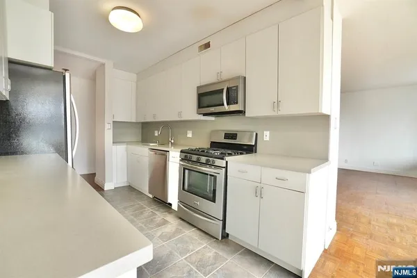 a kitchen with stainless steel appliances granite countertop a refrigerator and a stove
