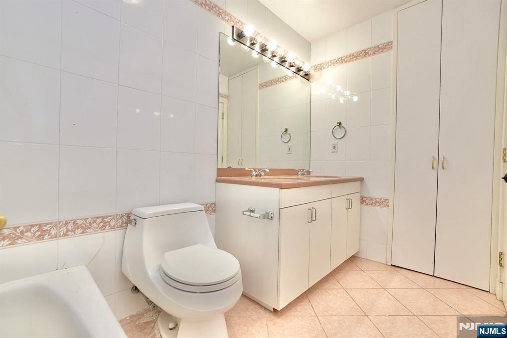 5 Horizon Road, Unit 203 Fort Lee, NJ 07024 - Photo 20 of 27 a bathroom with a granite countertop sink toilet a mirror a vanity and shower