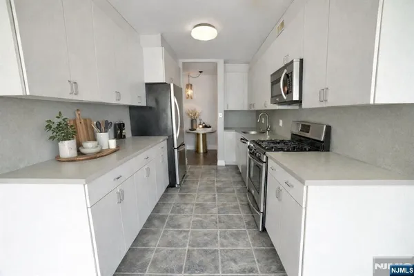 a kitchen with kitchen island granite countertop a refrigerator a stove top oven a sink and dishwasher