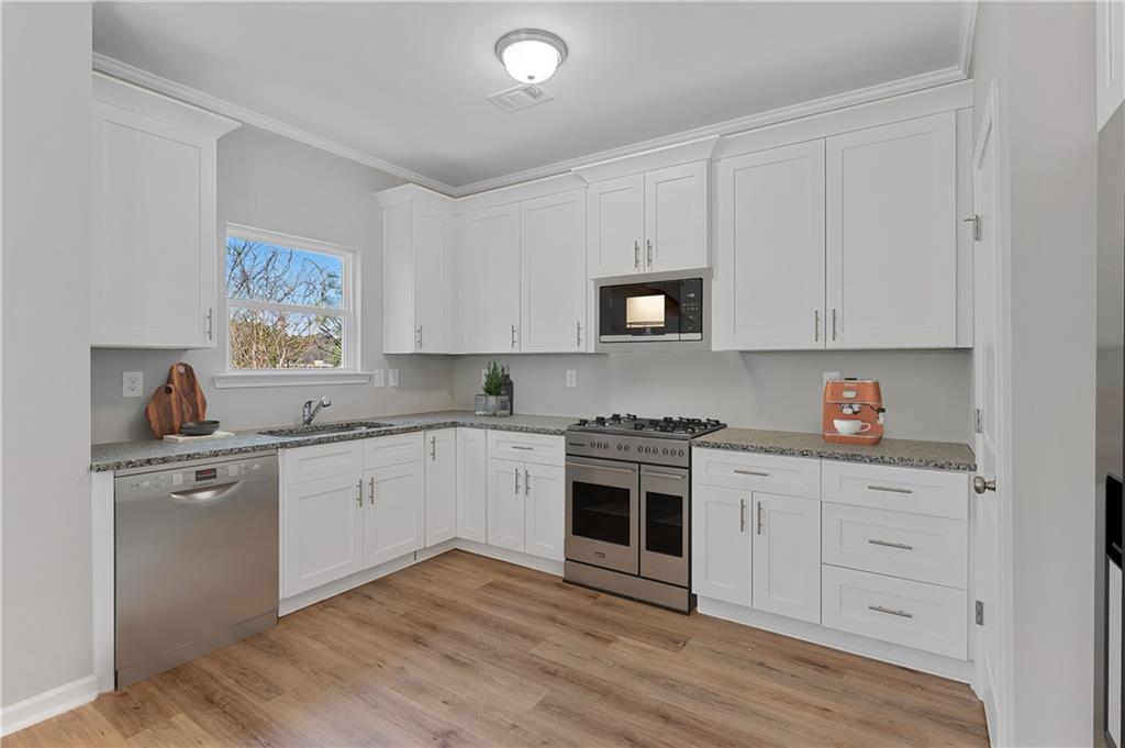 2832 Laurel Ridge Circle Atlanta, GA 30344 - Photo 8 of 28 a kitchen with stainless steel appliances granite countertop a stove top oven a sink and dishwasher with wooden floor