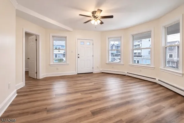 a view of an empty room with window and wooden floor