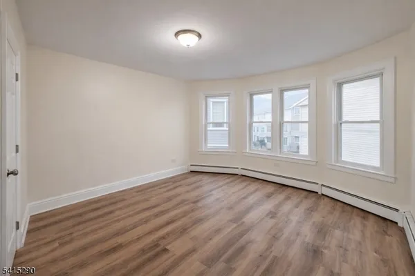 a view of an empty room with wooden floor and window