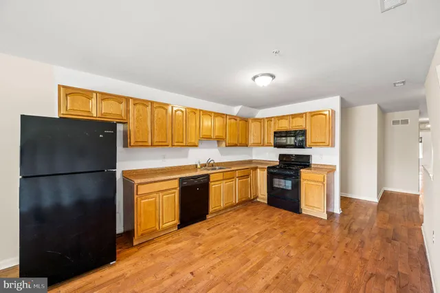 a kitchen with a refrigerator a stove top oven a sink dishwasher and wooden cabinets with wooden floor