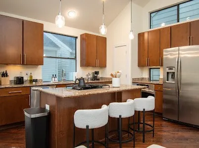 a kitchen with stainless steel appliances granite countertop a refrigerator a sink a stove a dining table and chairs