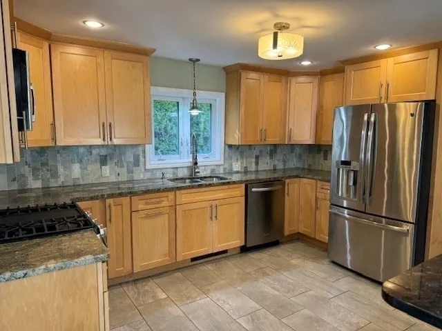 a kitchen with stainless steel appliances granite countertop a stove a sink dishwasher a refrigerator and cabinets