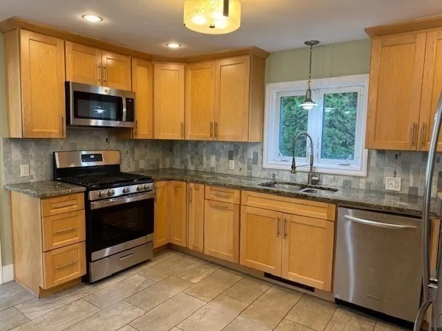 a kitchen with stainless steel appliances granite countertop a stove a sink and a microwave