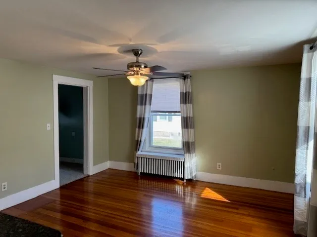 a view of an empty room with wooden floor and a window