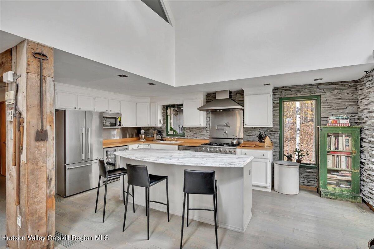 126 Storks Nest Road Round Top, NY 12473 - Photo 10 of 44 a kitchen with stainless steel appliances kitchen island a table chairs refrigerator and stove