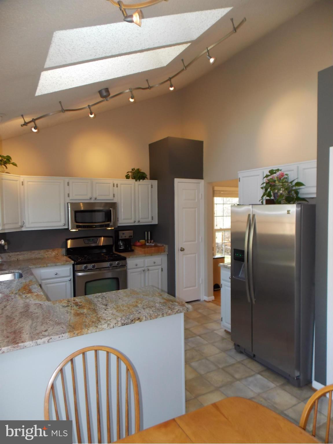 429 Deer Path Avenue Southwest Leesburg, VA 20175 - Photo 8 of 30 a kitchen with stainless steel appliances kitchen island granite countertop a refrigerator a stove and a sink with wooden floor