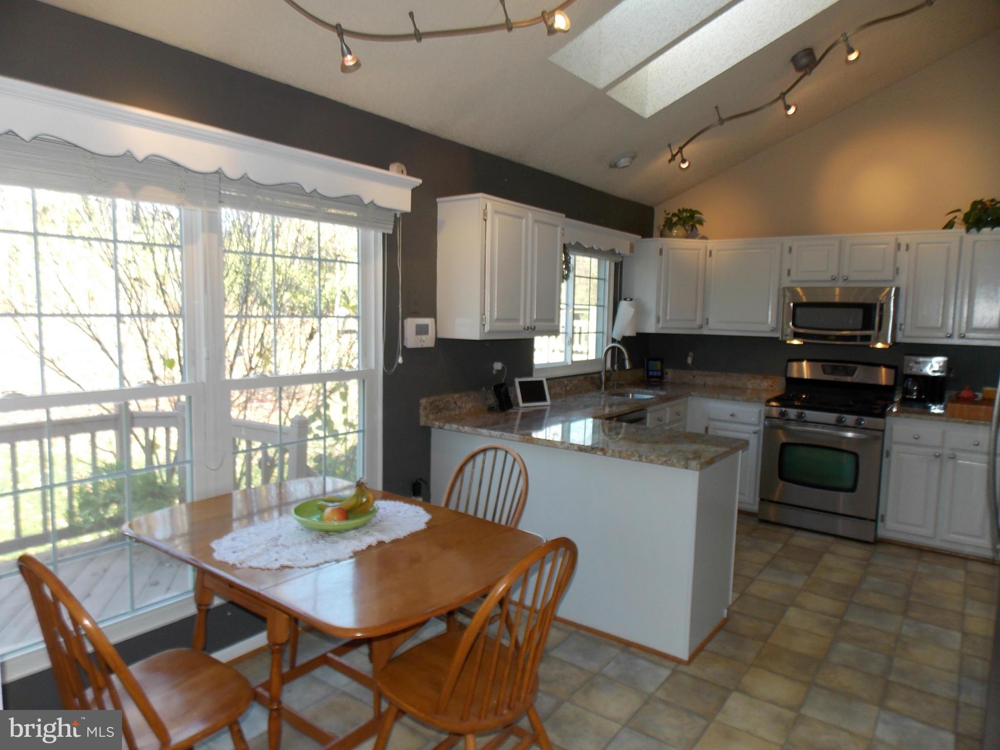 429 Deer Path Avenue Southwest Leesburg, VA 20175 - Photo 10 of 30 a kitchen with stainless steel appliances kitchen island granite countertop a stove a sink a microwave a dining table and chairs