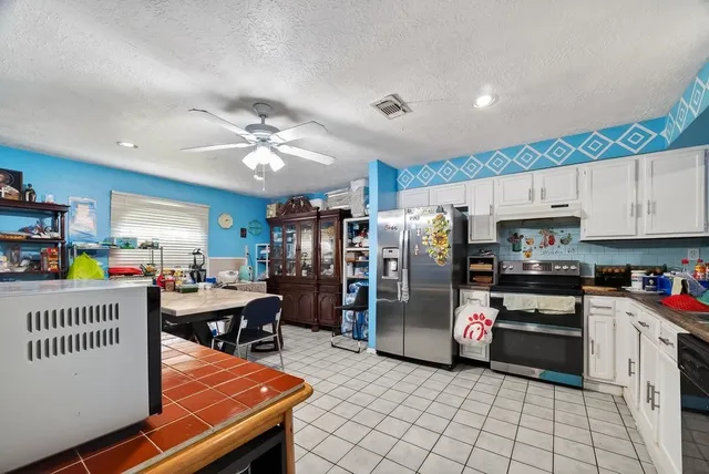 a kitchen with stainless steel appliances kitchen island granite countertop a refrigerator oven a sink dishwasher and a dining table with wooden floor