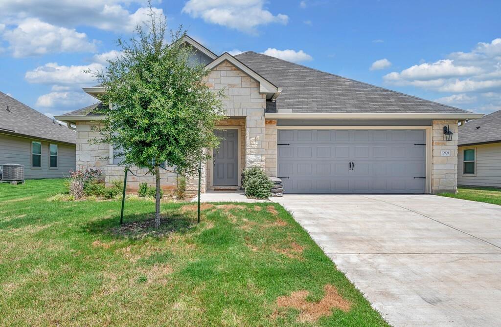 10909 Hollister Lane Waco, TX 76708 - Photo 1 of 1 View of front facade featuring stone siding, a garage, driveway, and a front yard