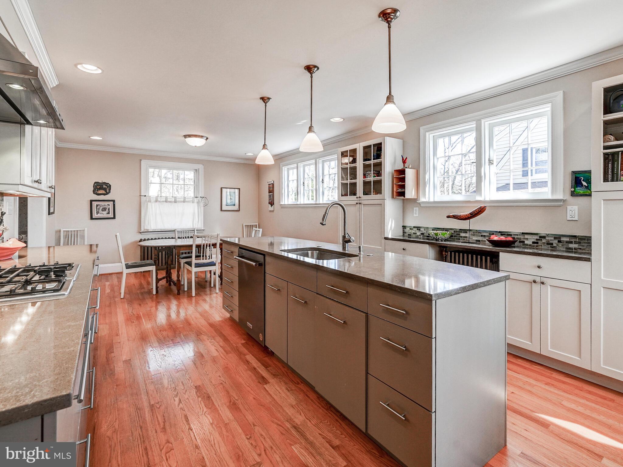 207 Cedarcroft Road Baltimore, MD 21212 - Photo 18 of 50 a kitchen with granite countertop a stove a sink a dining table and chairs with wooden floor