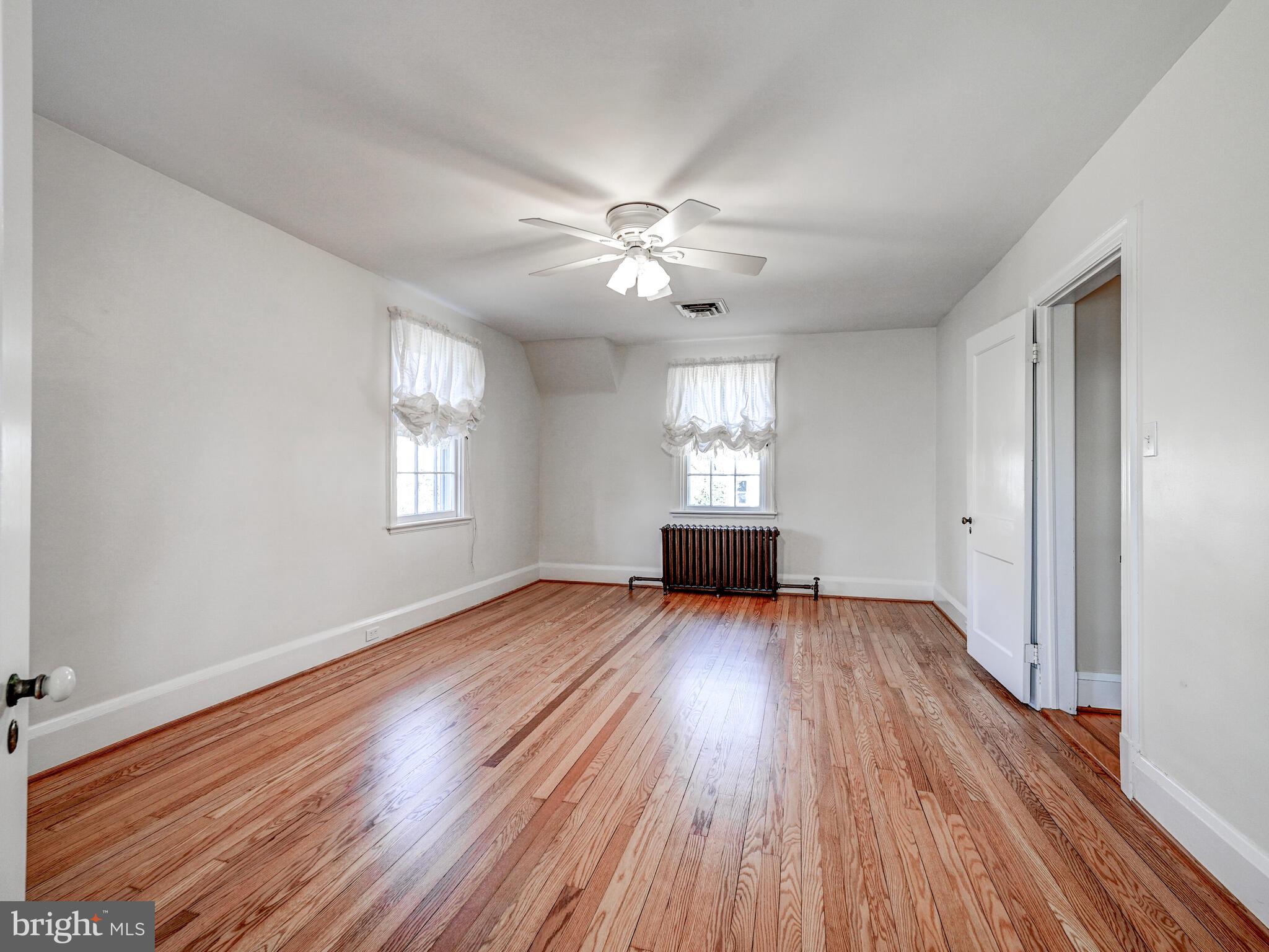 207 Cedarcroft Road Baltimore, MD 21212 - Photo 25 of 50 an empty room with wooden floor chandelier fan and windows