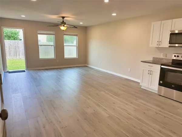 a view of an empty room with a window and wooden floor
