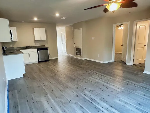 a large kitchen with a wooden floor and stainless steel appliances